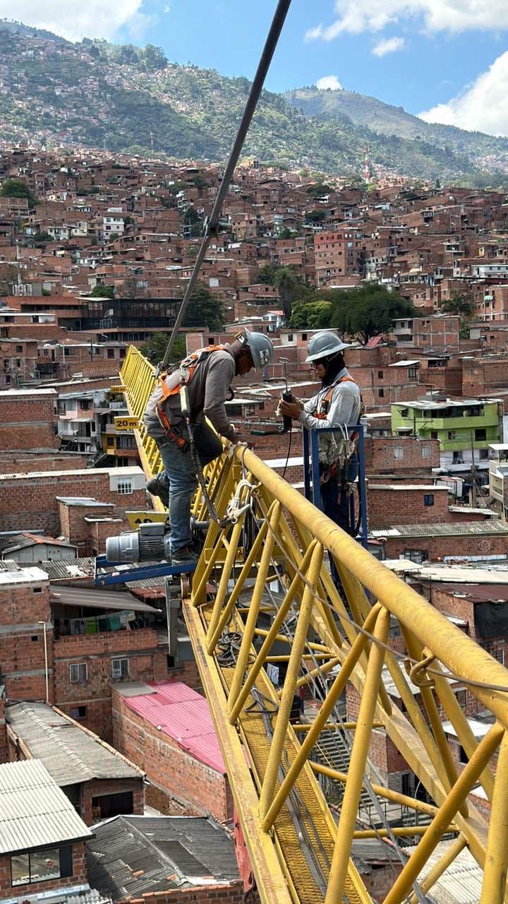 Técnicos de Progruas trabajando en la pluma de una torre grúa sobre Medellín